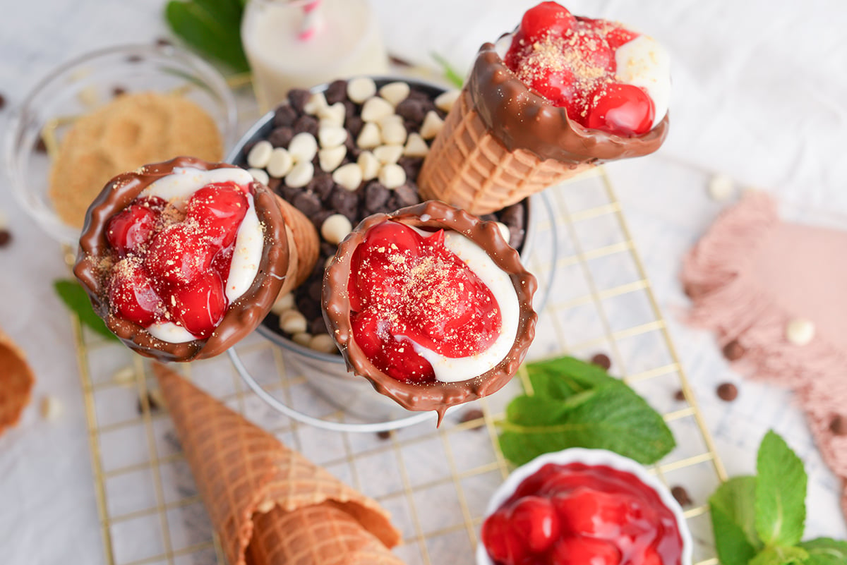 overhead shot of three cherry cheesecake cones in bucket of chocolate chips