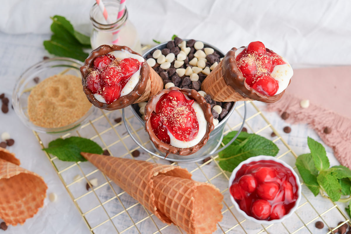 angled shot of three cherry cheesecake cones in bucket of chocolate chips