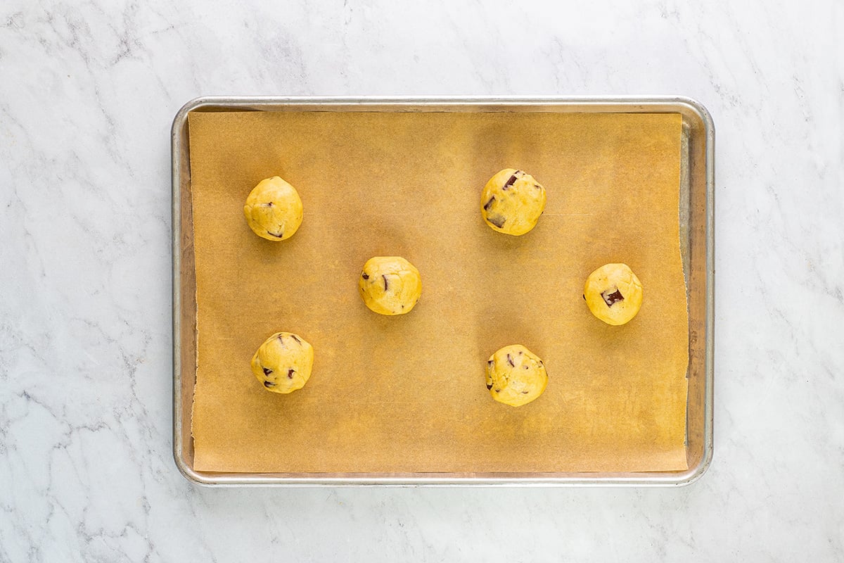 balled cookie dough on a parchment lined baking sheet