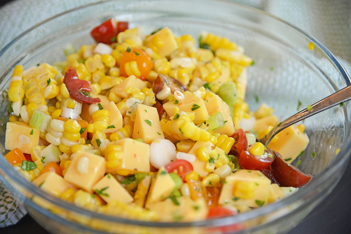 angled shot of spoon in bowl of cold corn salad