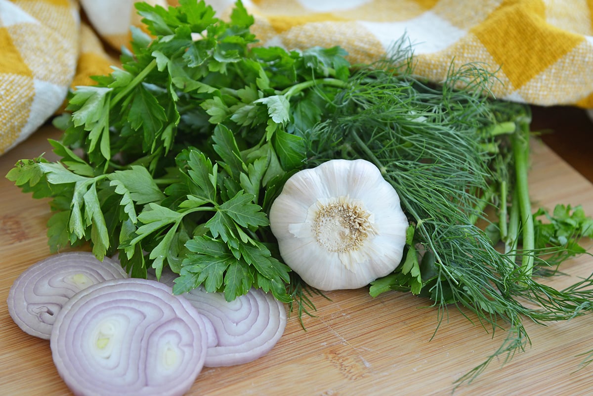 parsley, cilantro, dill, garlic and shallot on a cutting board