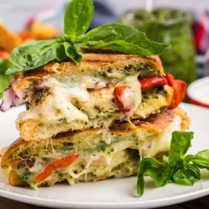straight on shot of Italian chicken panini halves on plate topped with basil