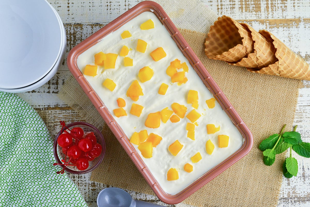 overhead of homemade mango ice cream in a pan with mango pieces on top