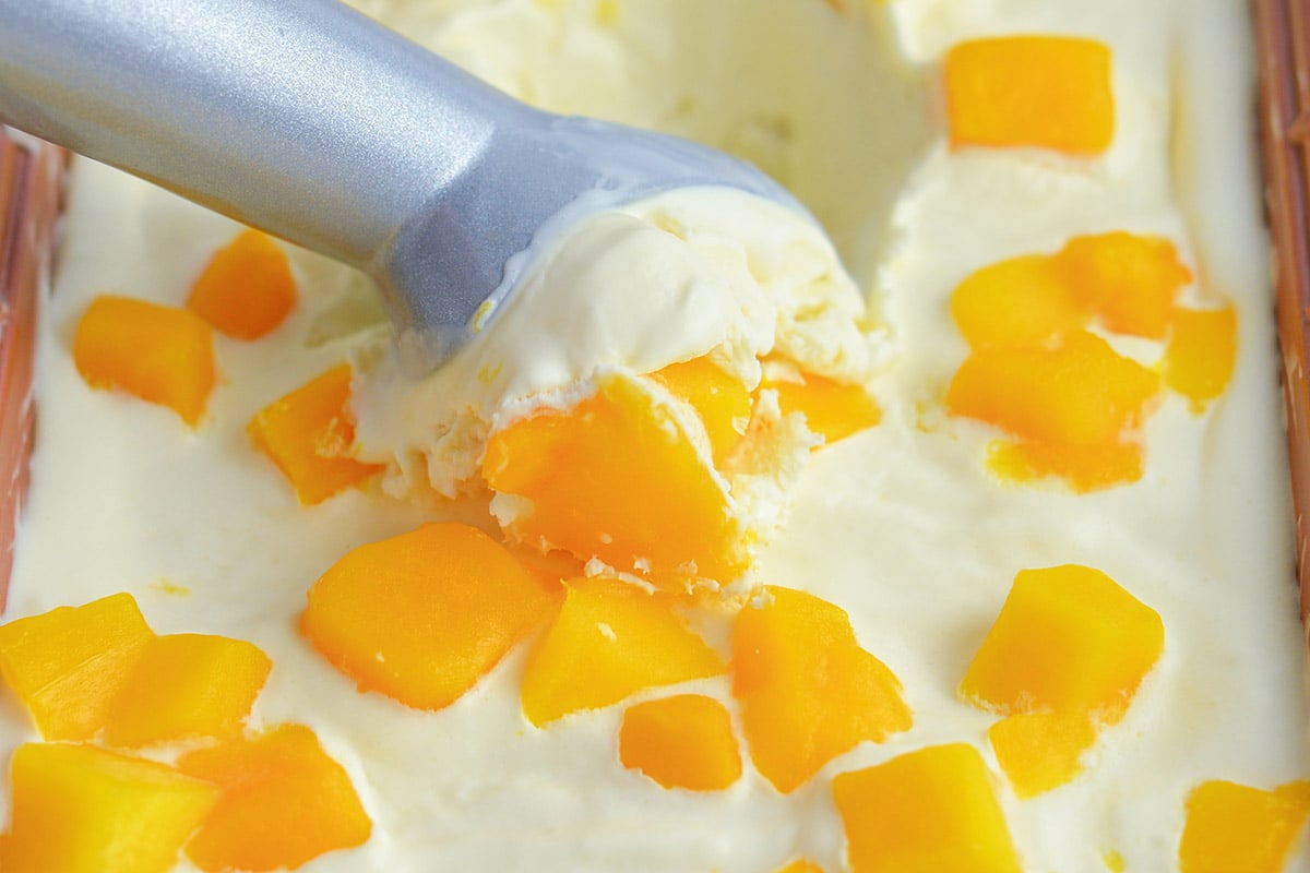 ice cream scoop scooping out frozen homemade ice cream with mangos