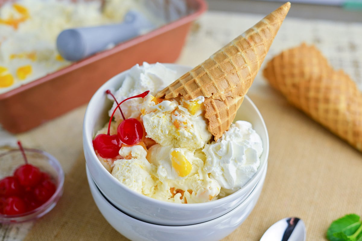 two bowls with mango ice cream recipe, cherries and a waffle cone