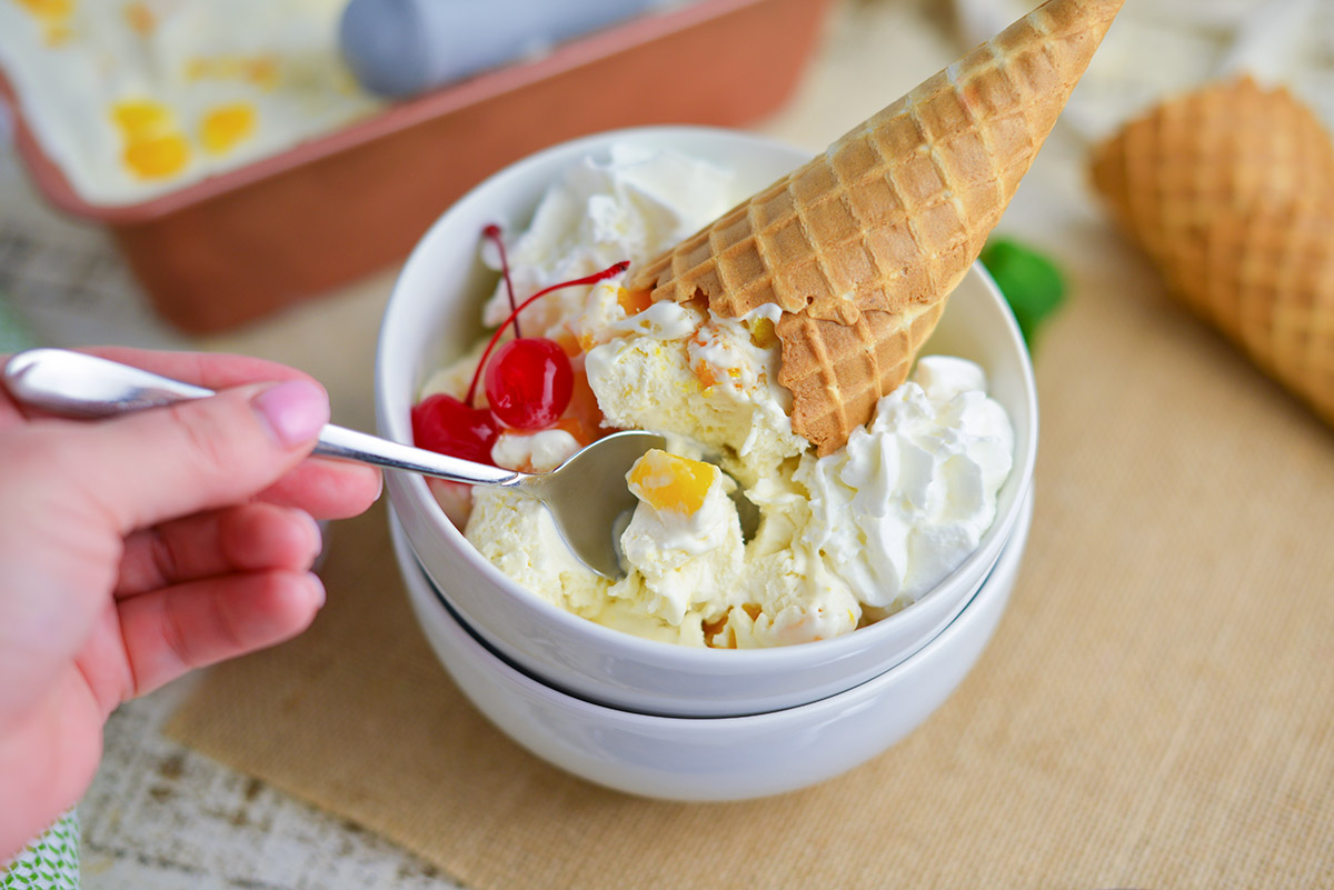 spoon eating no churn mango ice cream recipe with waffle cones and cherries