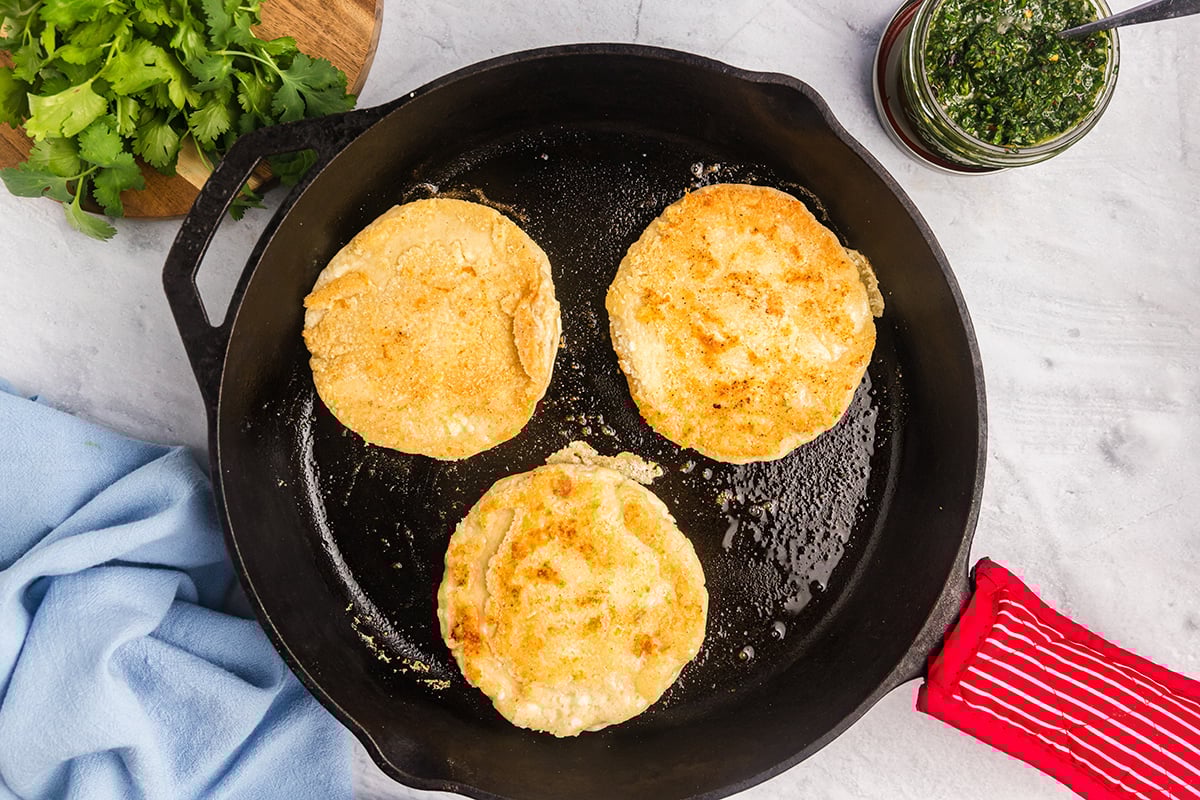 arepa con queso cooking in skillet