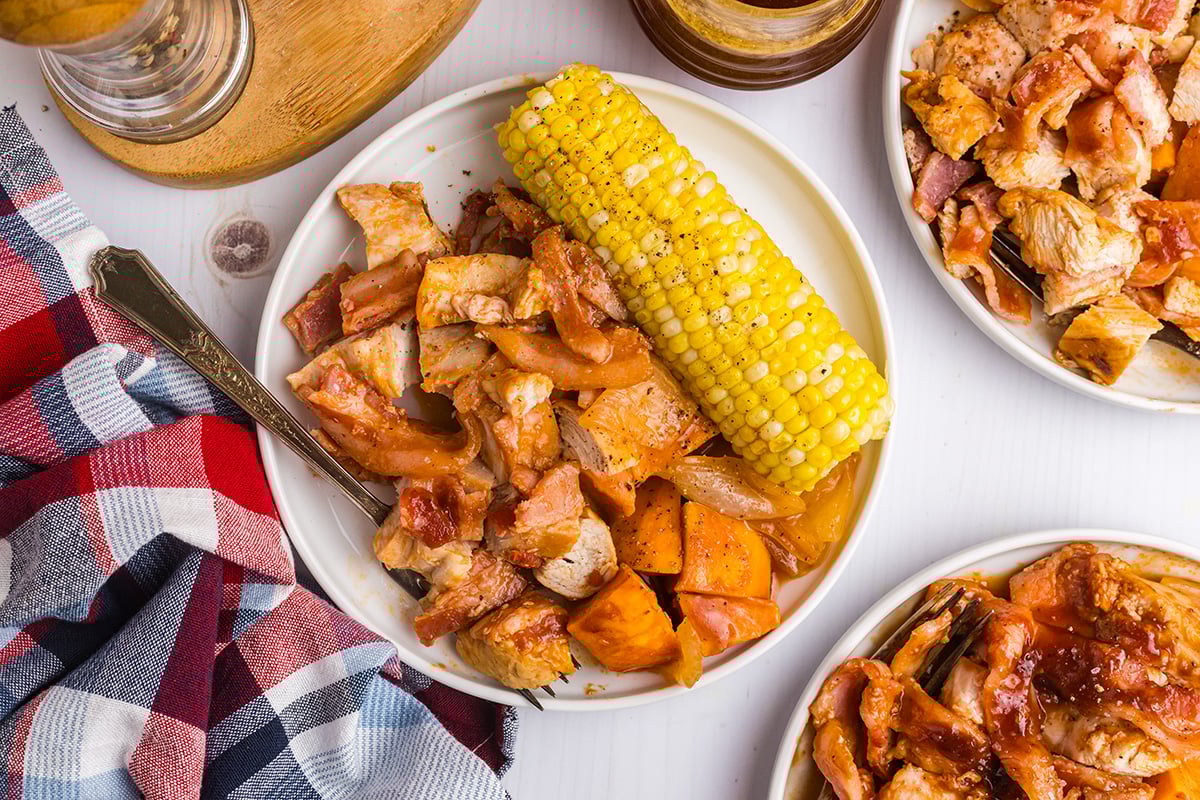 overhead shot of plate of bbq chicken, sweet potatoes and corn on the cob