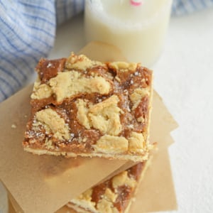 dulce de leche bars stacked between parchment with blue linen