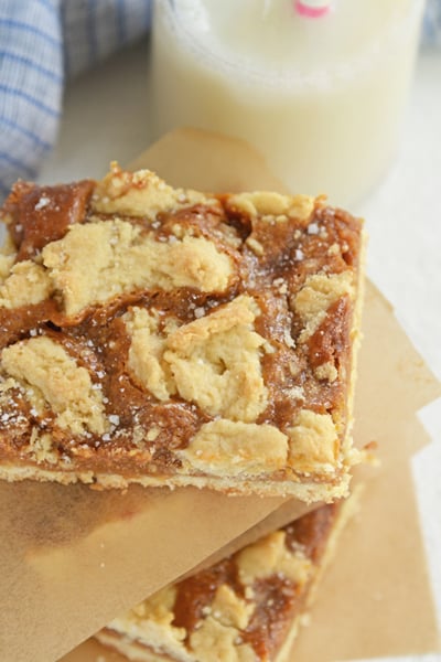 dulce de leche bars stacked between parchment with blue linen