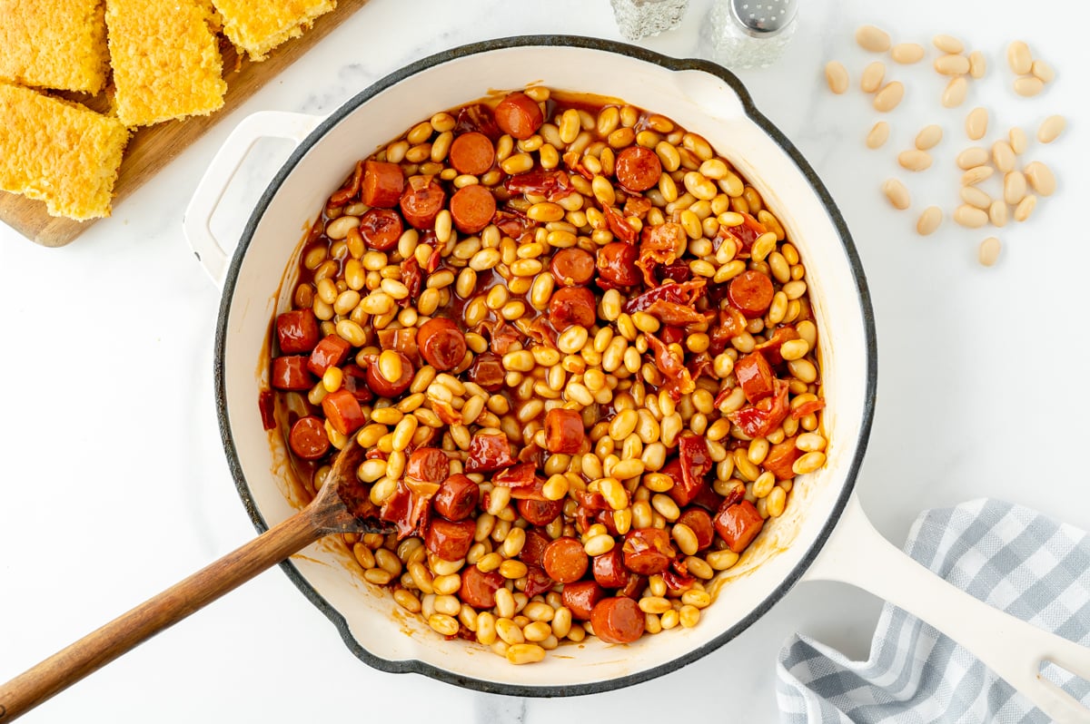 overhead shot of wooden spoon in skillet of beanie weenies