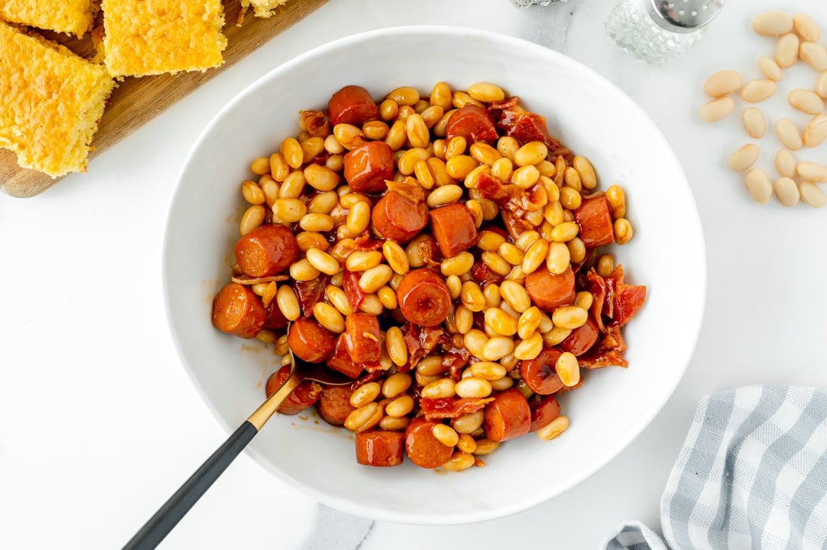 overhead shot of spoon in bowl of franks and beans