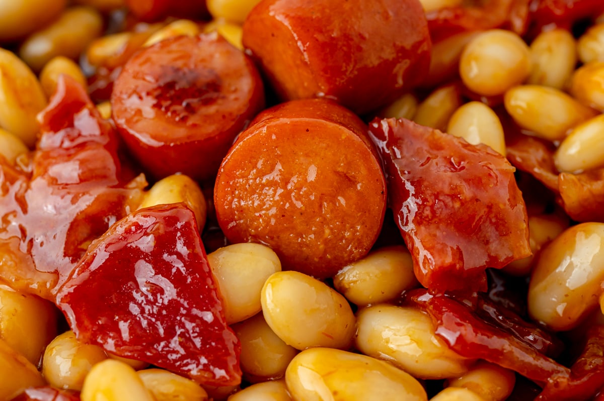close up shot of cut up hot dogs in beans