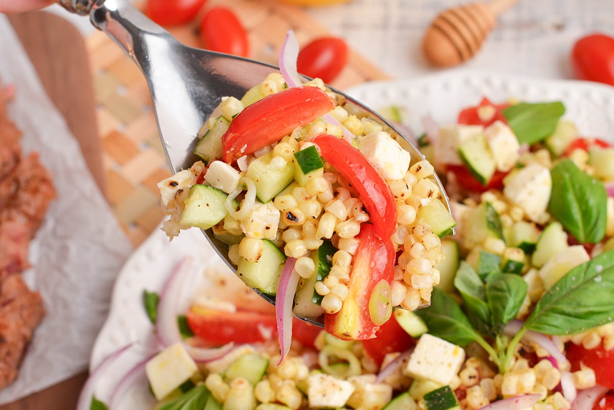 overhead shot of corn and tomato salad on a serving spoon