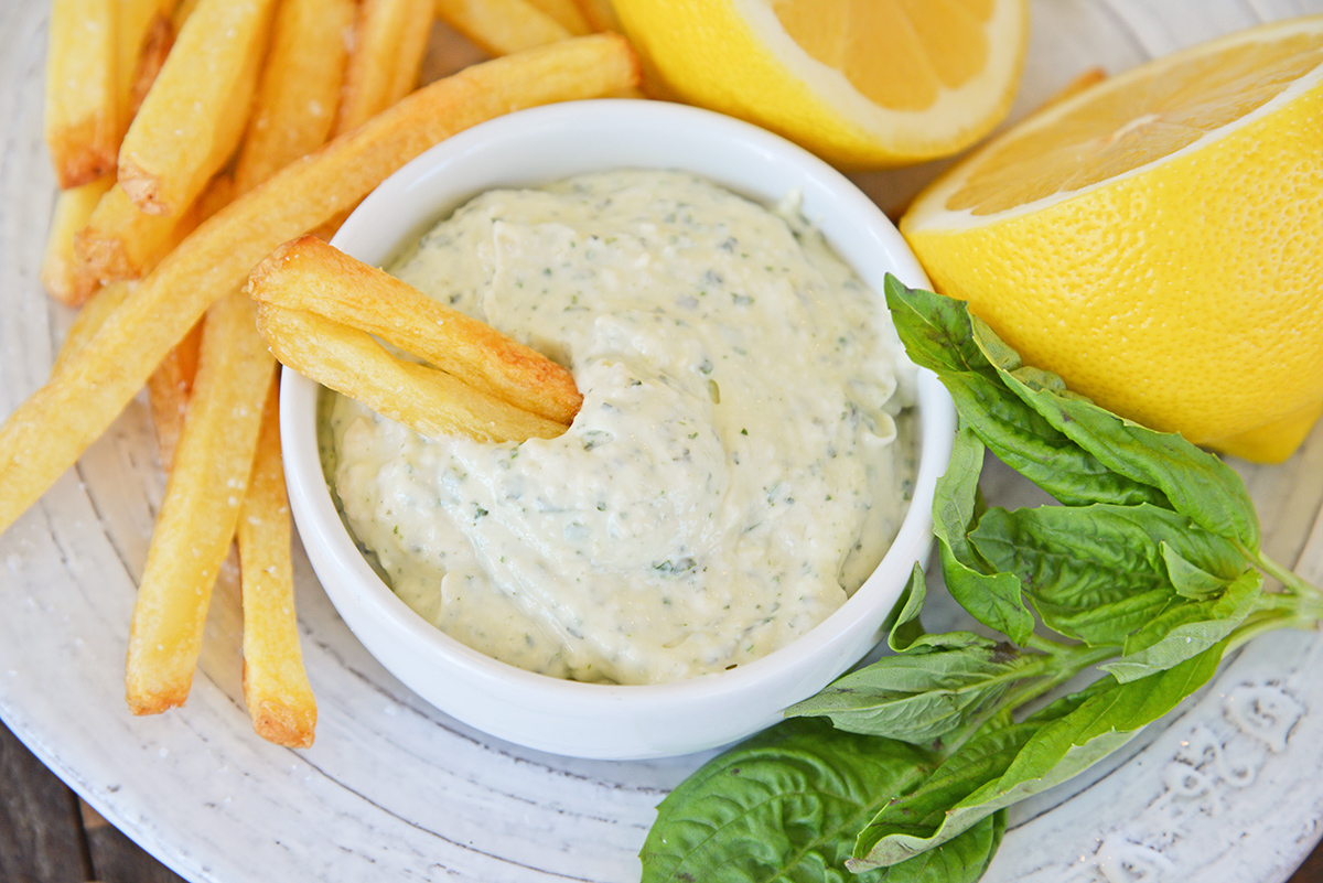 angled shot of french fries dipping into basil pesto aioli