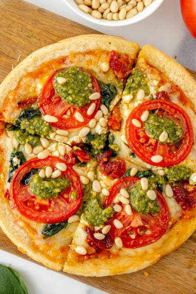 sliced tomato pesto pizza on cutting board