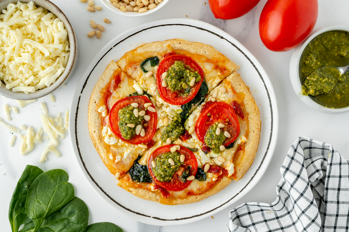 sliced tomato pesto pizza on plate