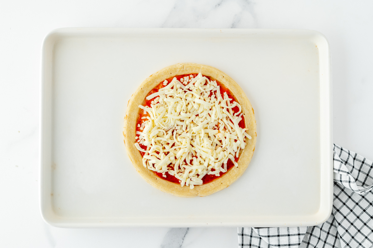 cheese added to pizza crust with sauce