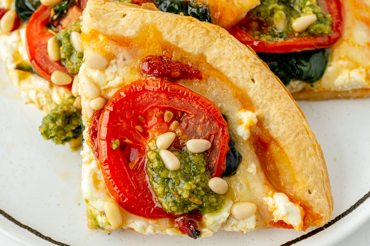 close up shot of slice of pesto pizza on plate