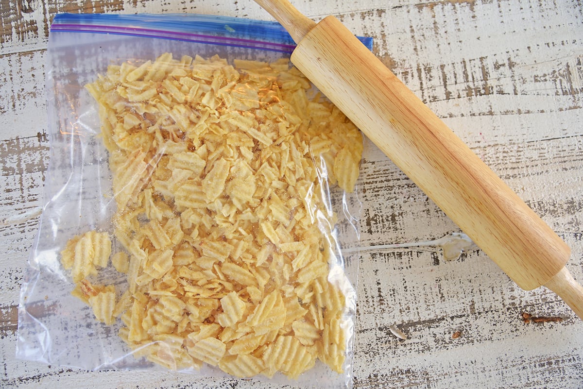 overhead shot of crushed potato chip cookies in a bag with a rolling pin