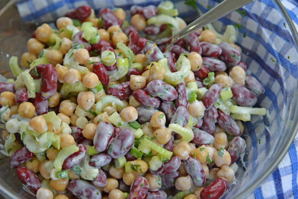 mixing beans together with yogurt, scallions and celery