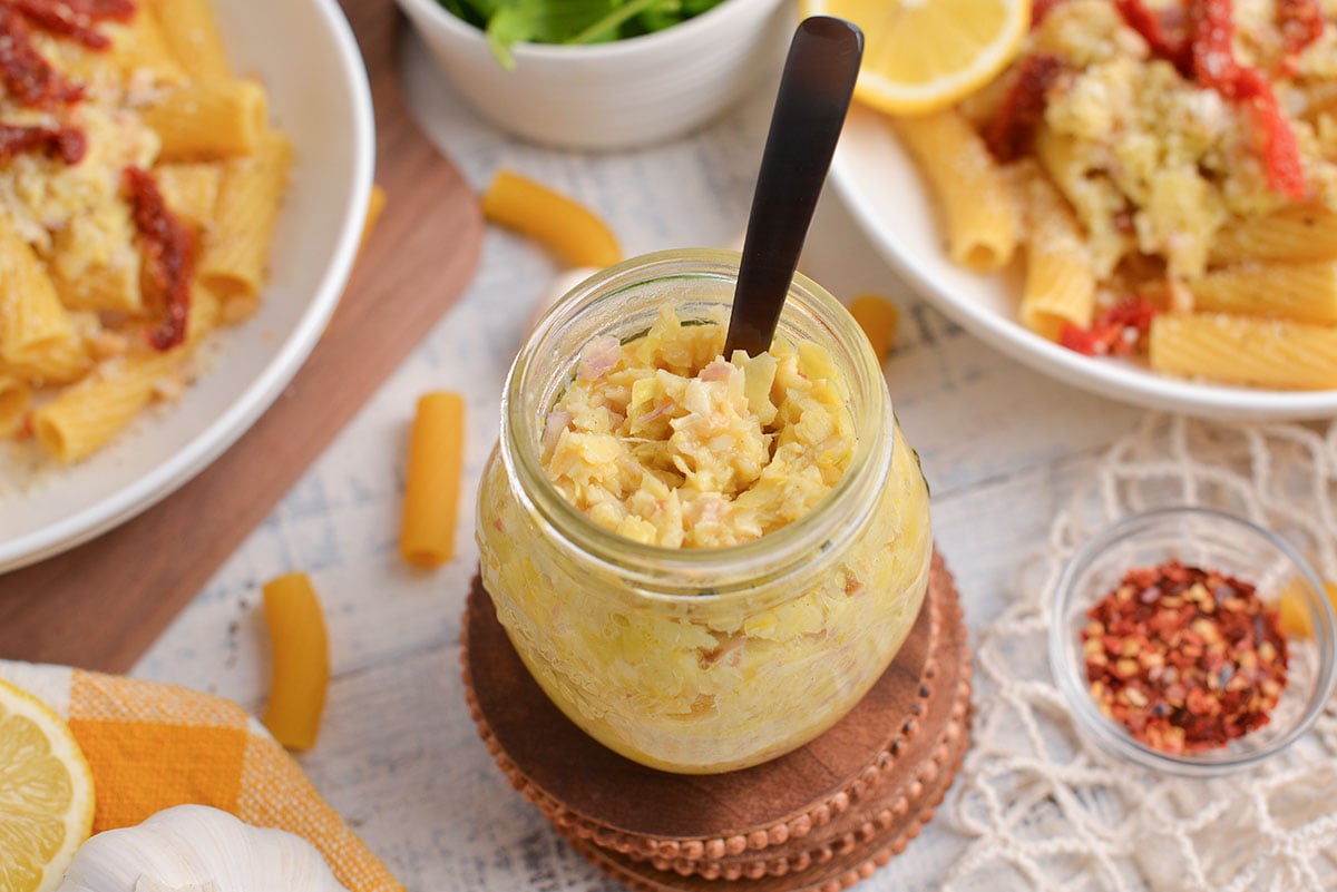 angled shot of spoon in jar of lemon pesto