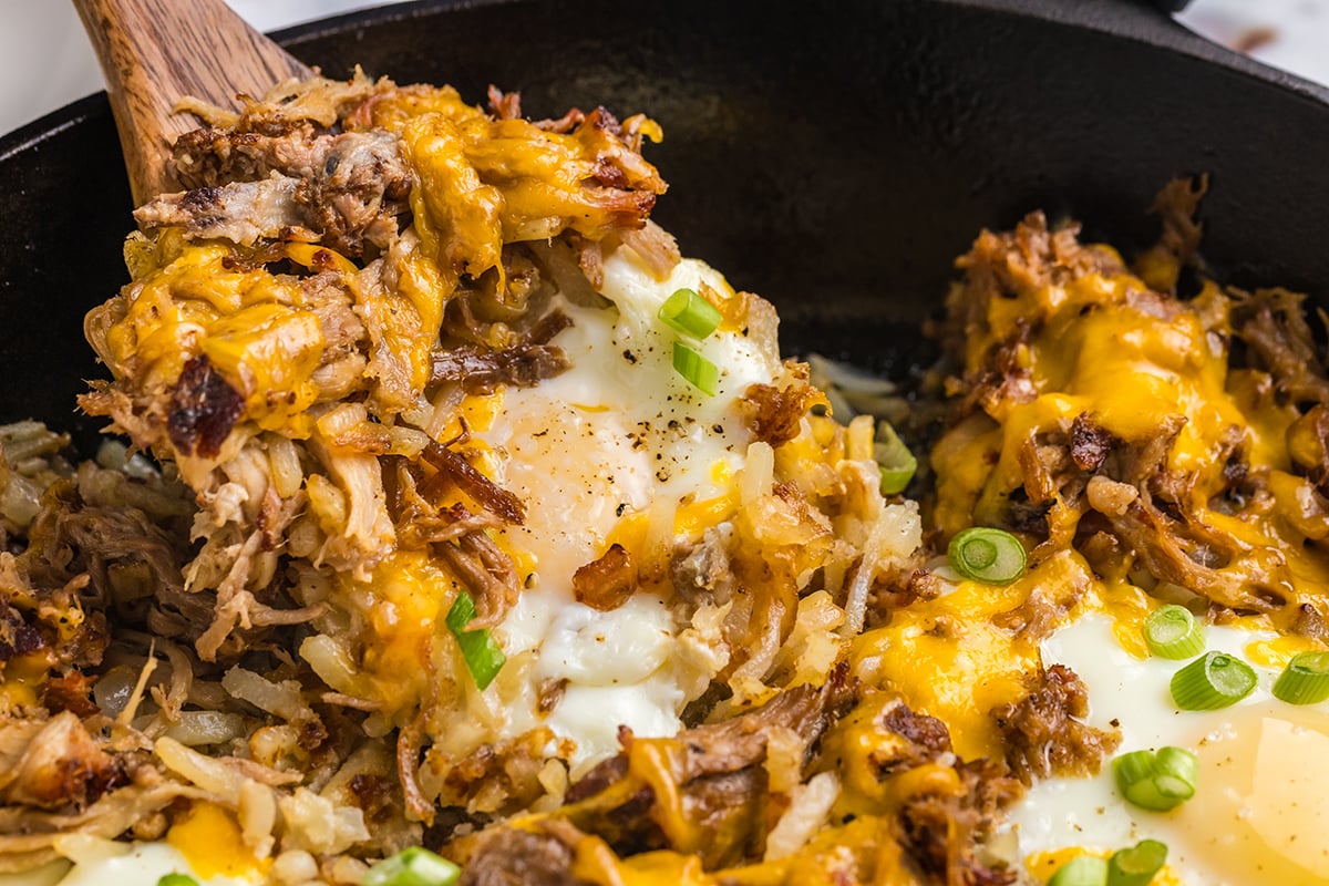 angled shot of wooden spoon in pulled pork hash skillet