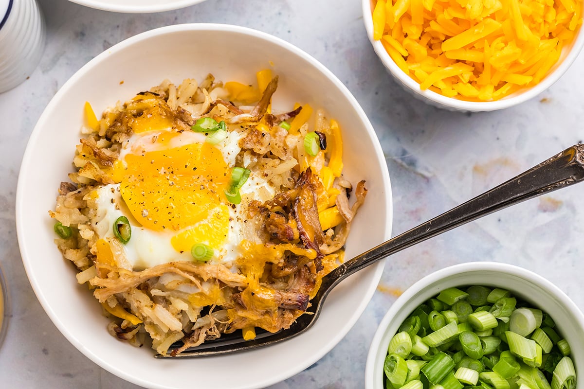 overhead shot of fork in bowl of pulled pork hash