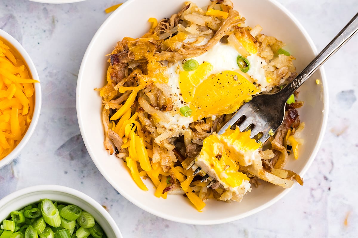 overhead shot of fork digging into bowl of bbq pulled pork hash