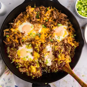 overhead shot of wooden spoon in bbq pulled pork hash in skillet