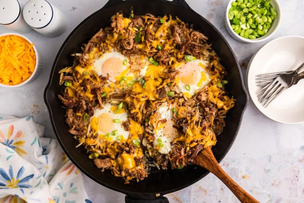 overhead shot of wooden spoon in bbq pulled pork hash in skillet