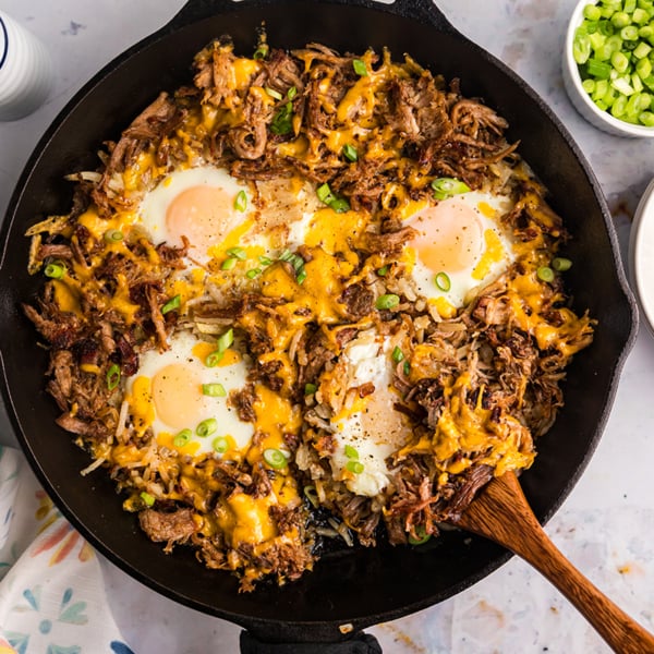 overhead shot of wooden spoon in bbq pulled pork hash in skillet