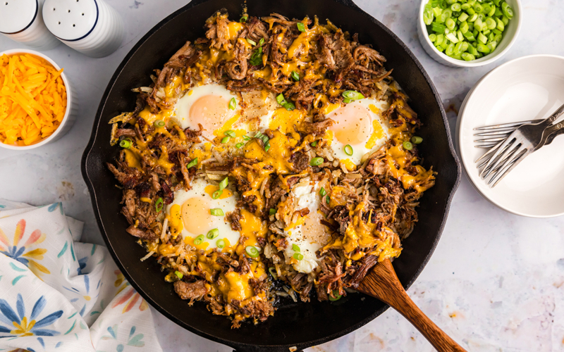 overhead shot of wooden spoon in bbq pulled pork hash in skillet
