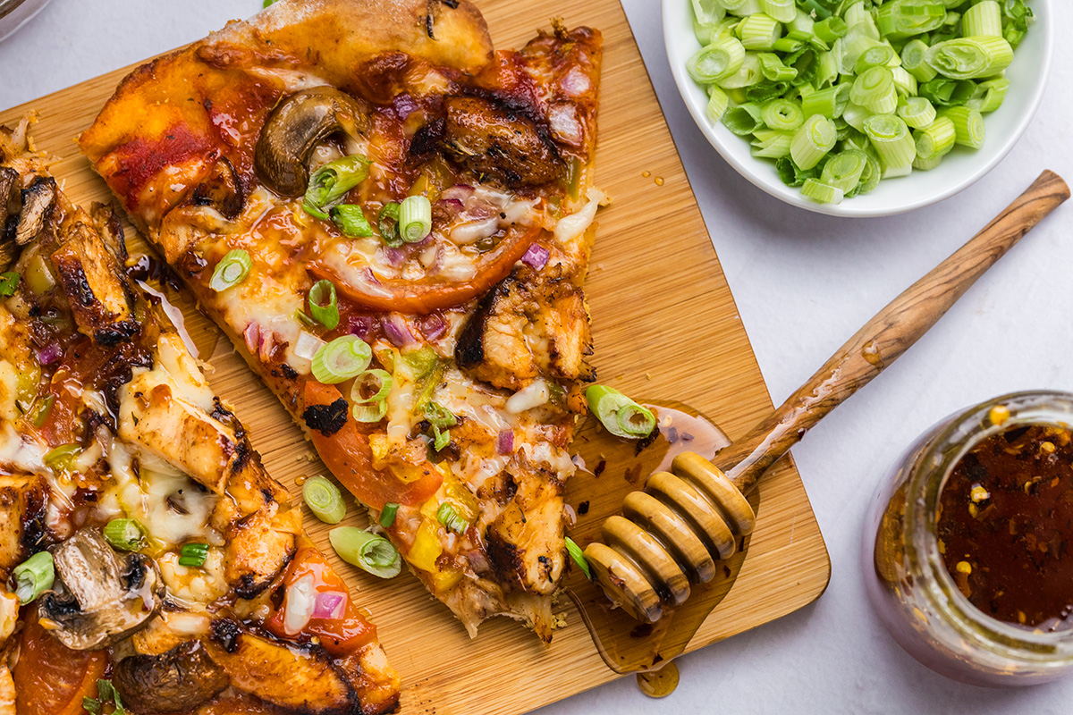 overhead shot of slices of pizza on board with honey