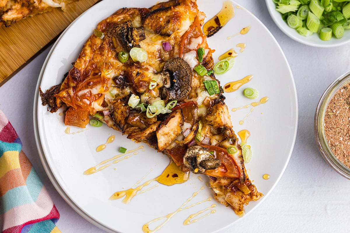 overhead shot of honey drizzled over slice of pizza on plate