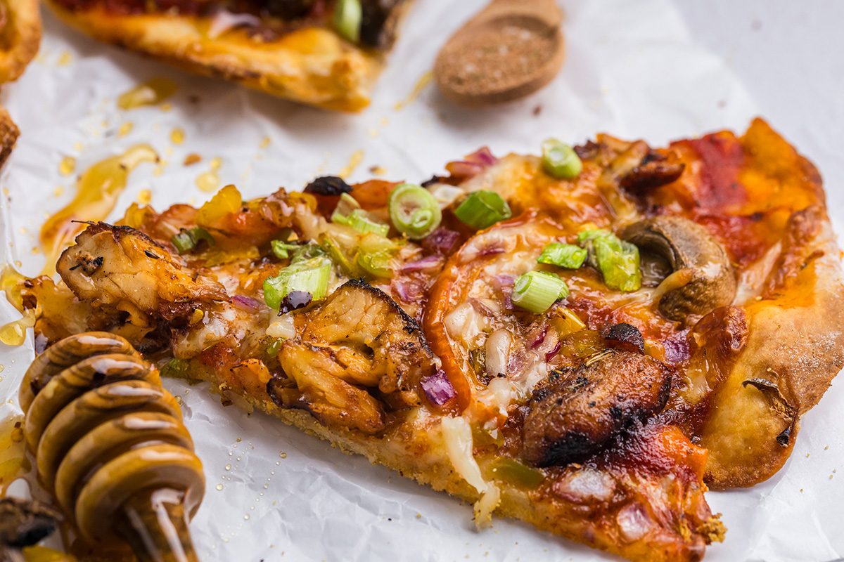 close up angled shot of slice of jerk chicken pizza