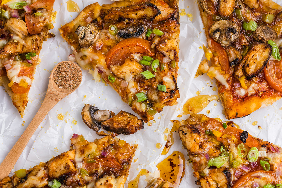 overhead shot of bites taken out of jerk chicken pizza slices