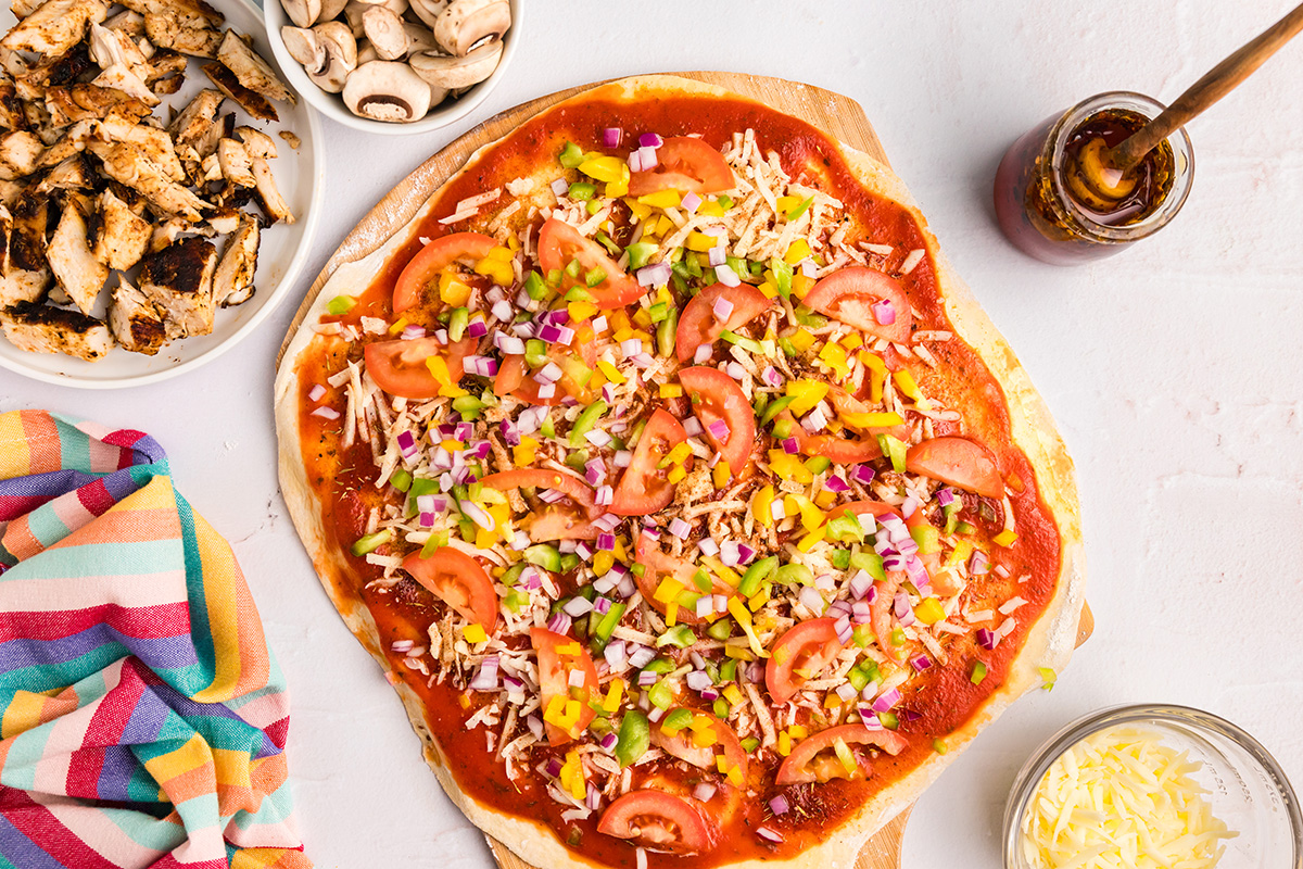 veggies sprinkled onto pizza dough