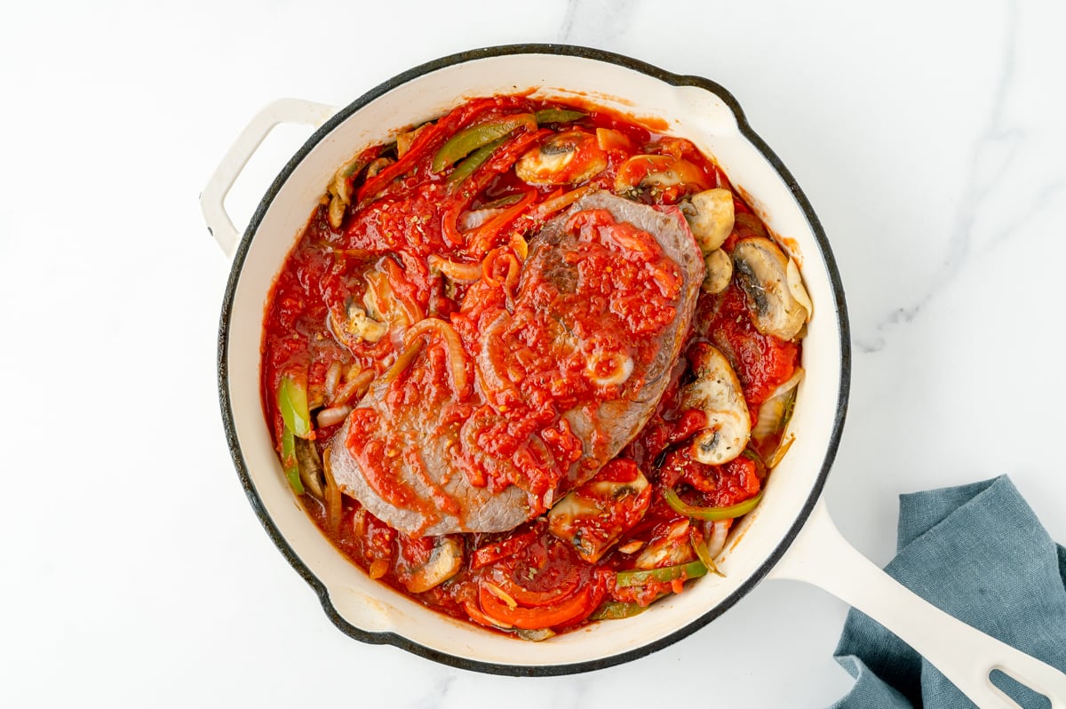 overhead shot of steak in pan with sauce and veggies