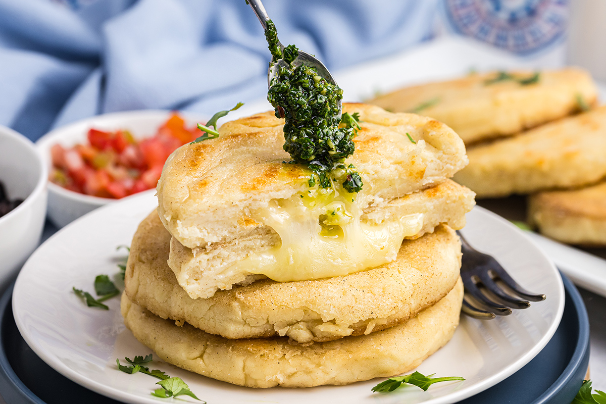 spooning chimichurri recipe onto arepas