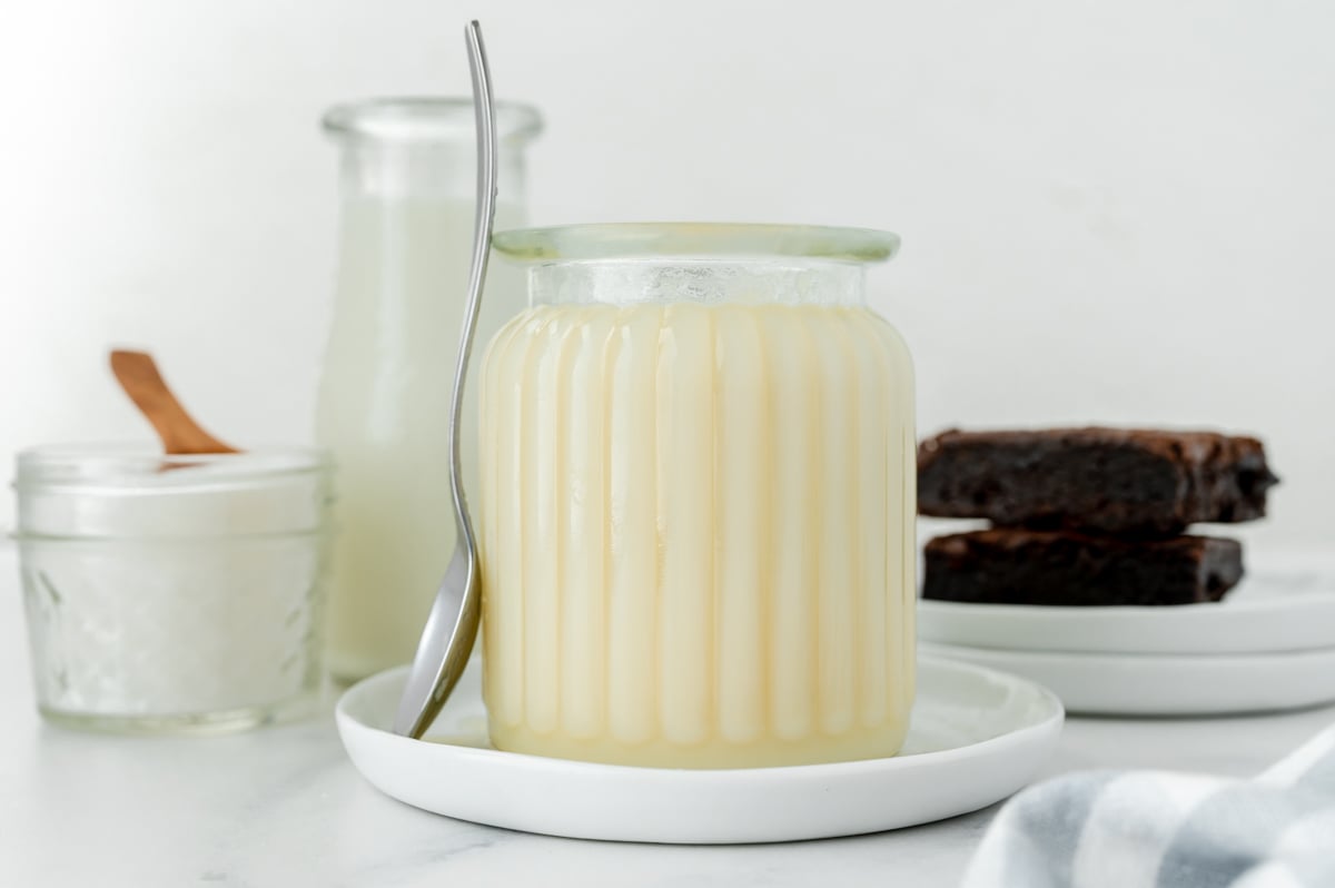 straight on shot of spoon leaning against jar of sweetened condensed milk