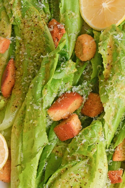 close up of romaine lettuce with garlic salad dressing, and fresh lemons