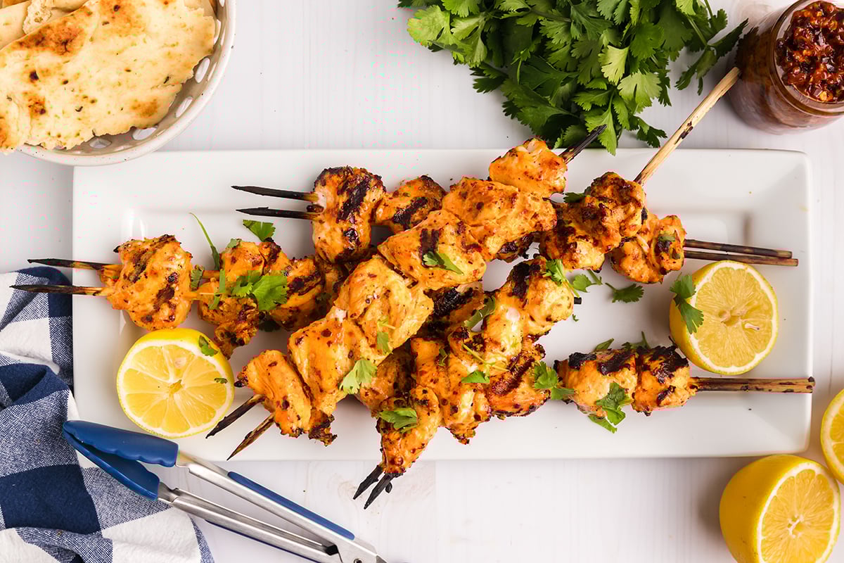 overhead shot of harissa chicken skewers on white tray