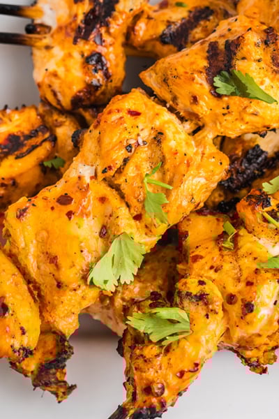 close up overhead shot of harissa chicken skewers on white tray
