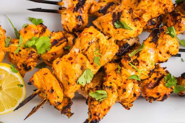 close up overhead shot of harissa chicken skewers on white tray