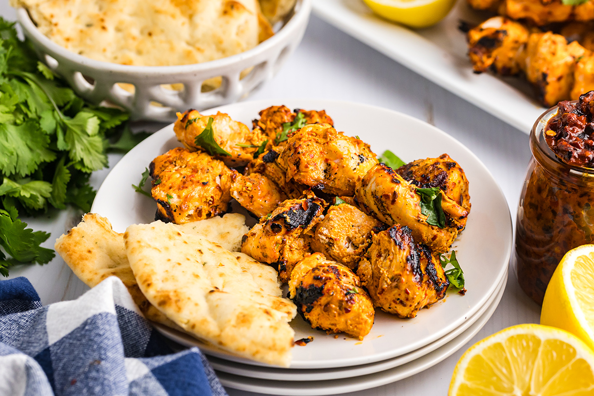 angled shot of spicy chicken pieces on plate with pita bread