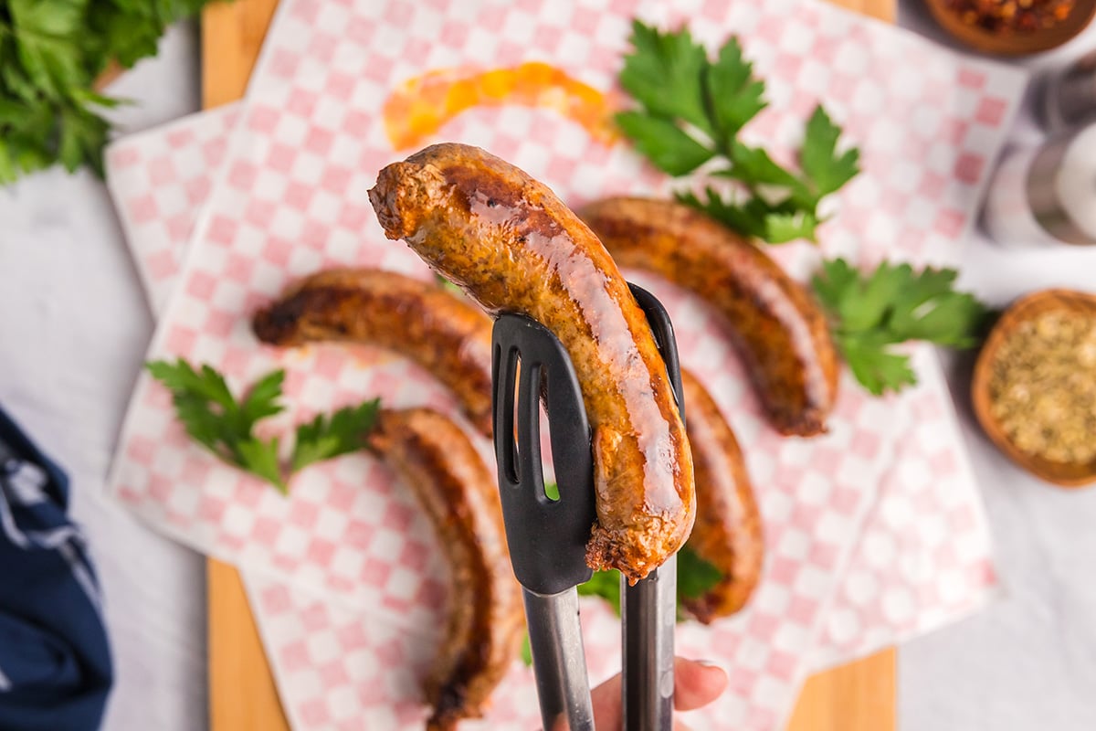overhead shot of homemade italian sausage held in tongs