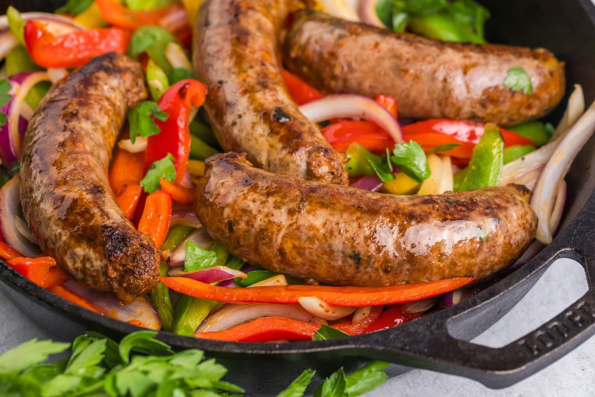 close up angled shot of homemade italian sausage in pan with peppers and onions