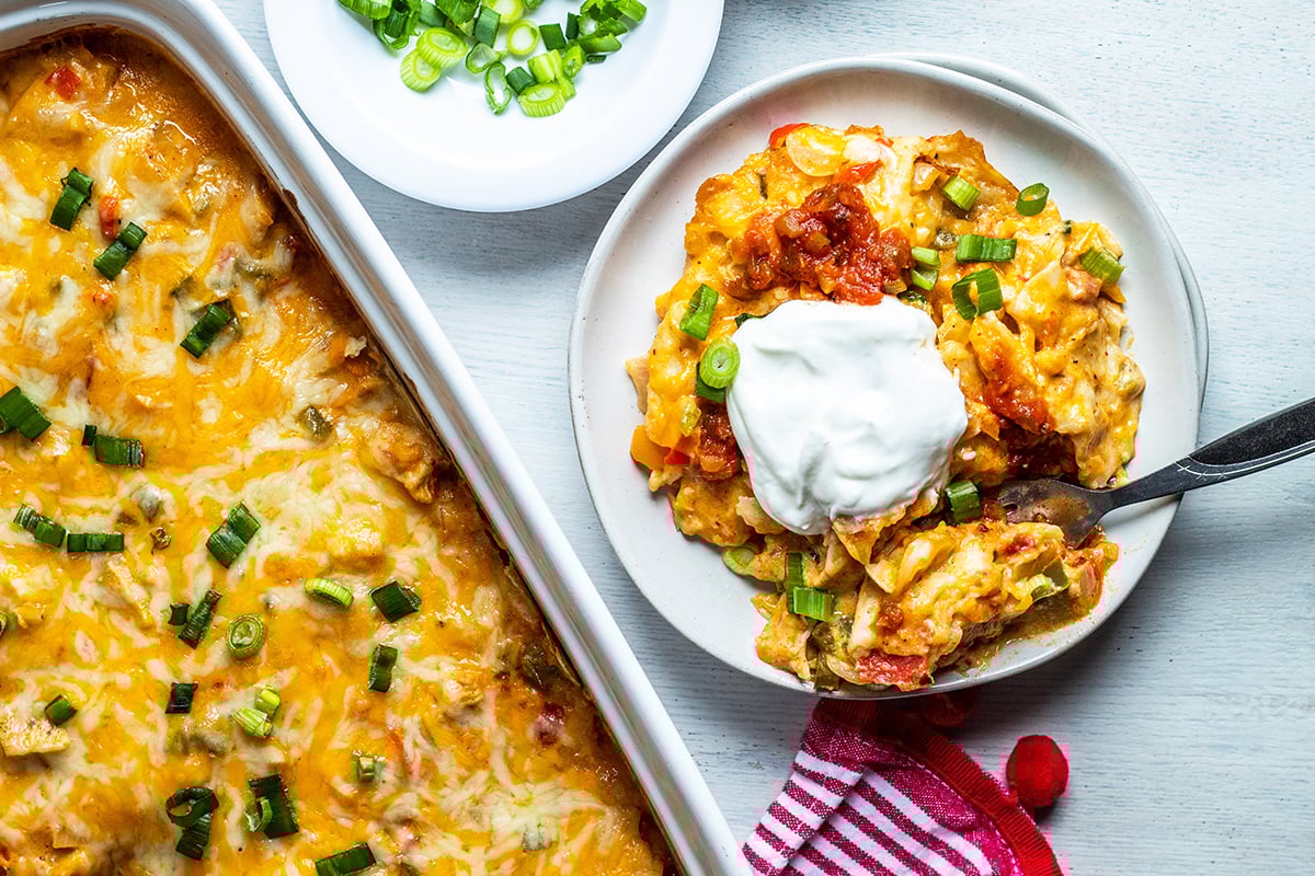 king ranch chicken casserole on a white plate with sour cream and salsa