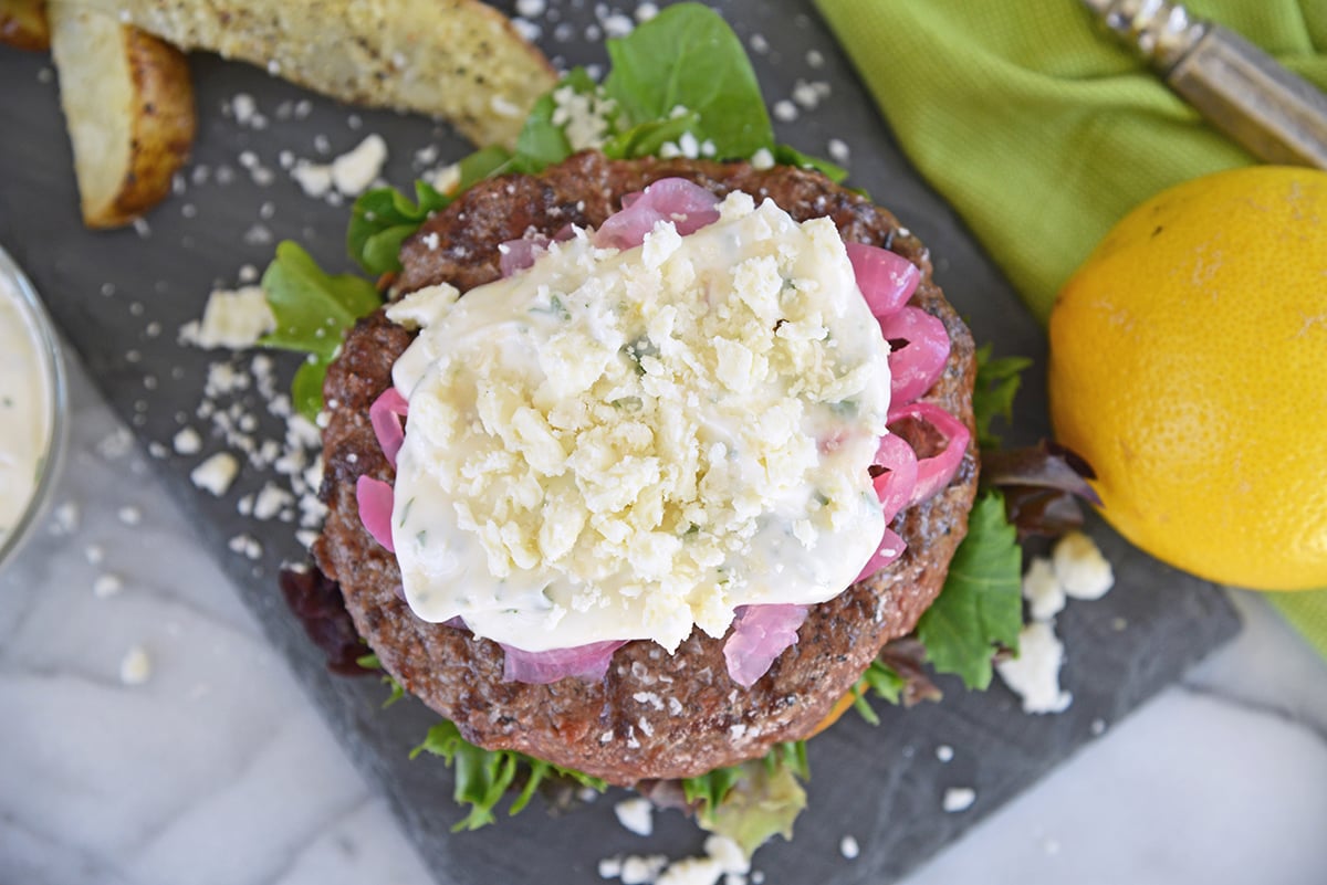 overhead of greek lamb burger with toppings on slate plate